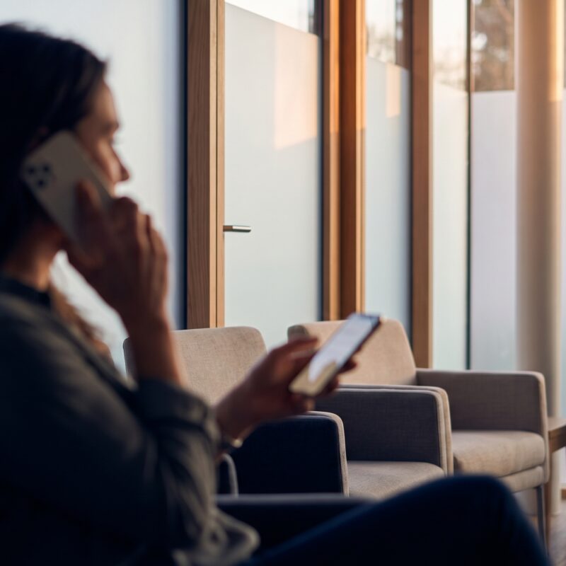 Patient in a modern clinic using a smartphone to experience the future of chatbots in healthcare.
